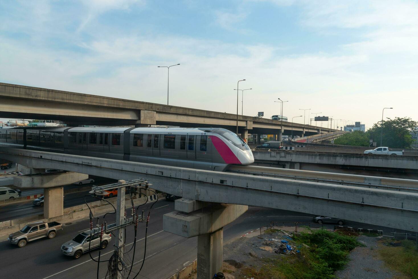 Bangkok, Thailand-November 28, 2023- Sky train of metropolitan rapid transit pink line running under tollway highway and traffic below at Laksi station. photo