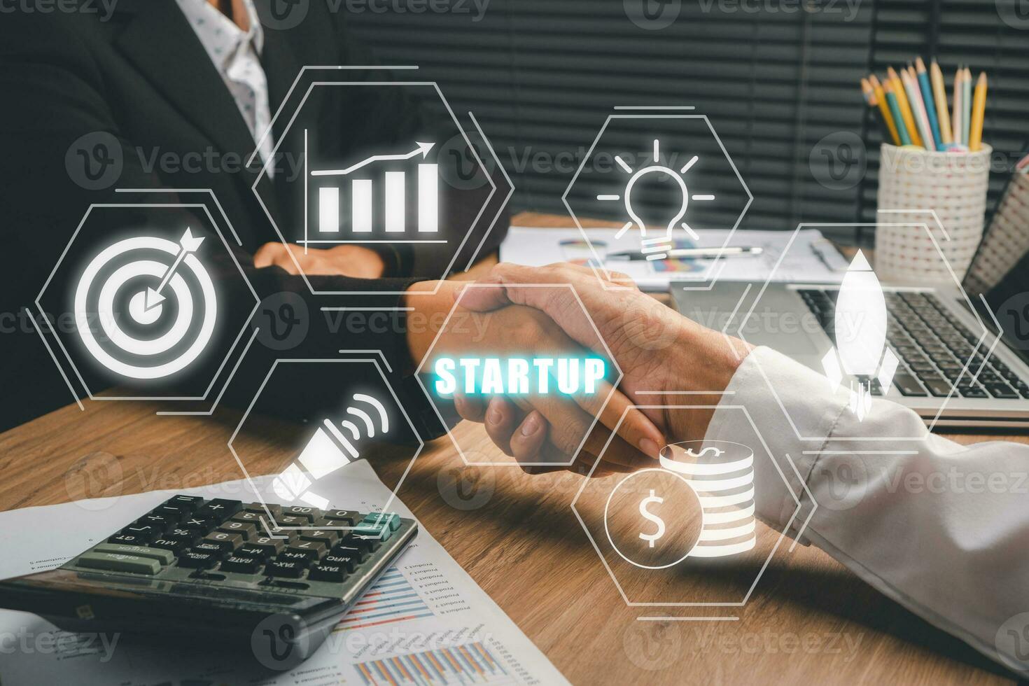 Startup business concept, Business team making handshake with his partner in office desk with icons startup on VR screen. photo