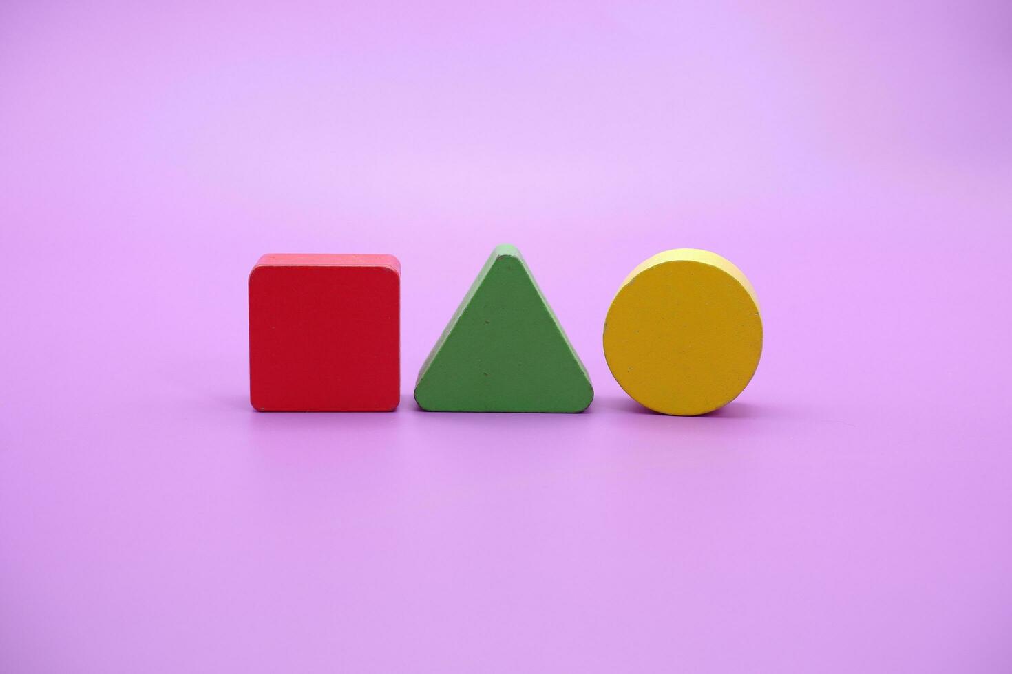 Set of colorful wooden shape toy. Square, triangle and round on Purple background photo