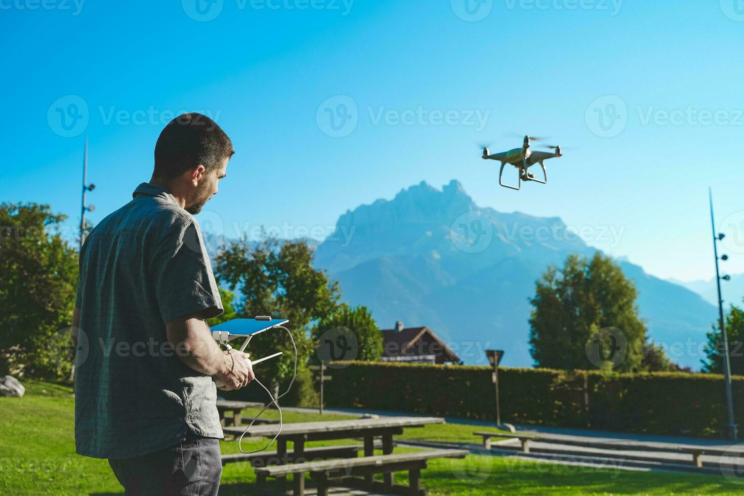 Young man flying drone on amazing mountain landscape. Man operating a drone with remote control taking aerial photos and videos.