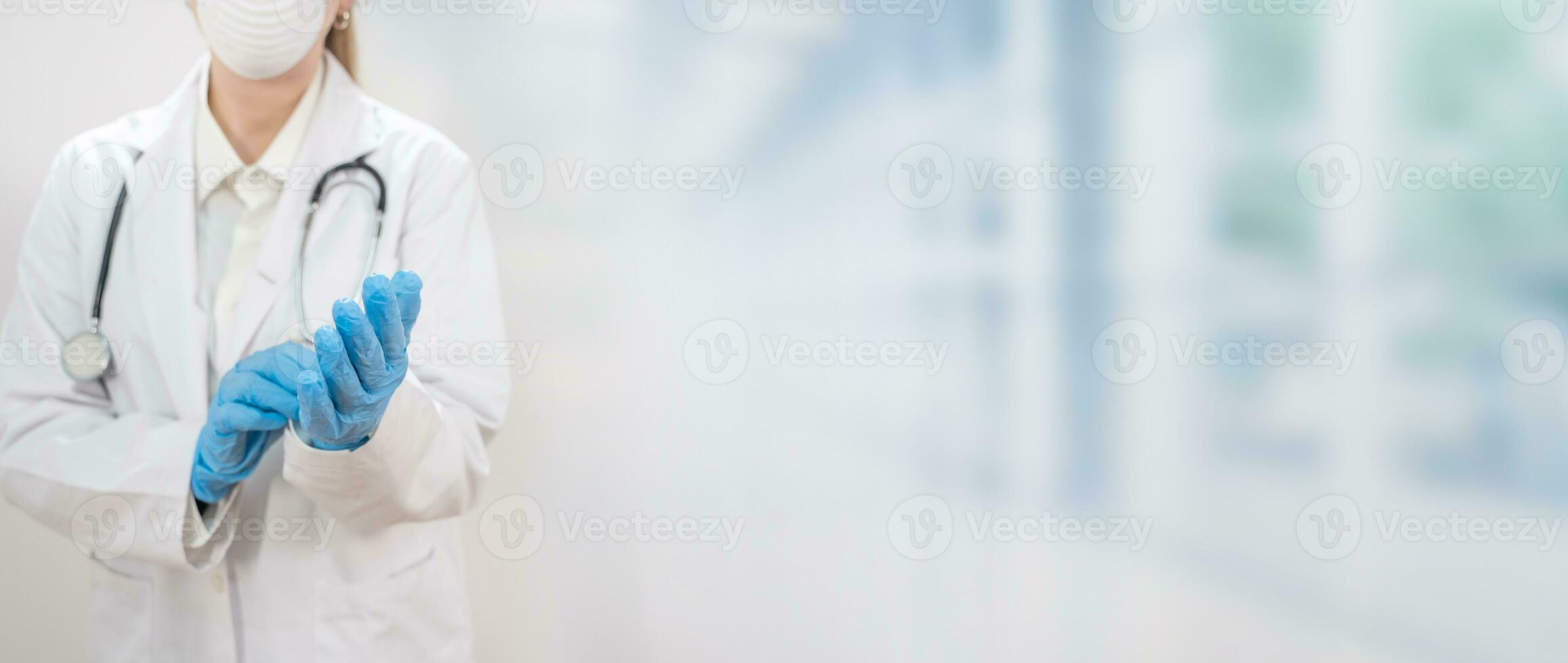 Banner with young attractive female doctor wearing blue gloves and blur hospital in the background. photo
