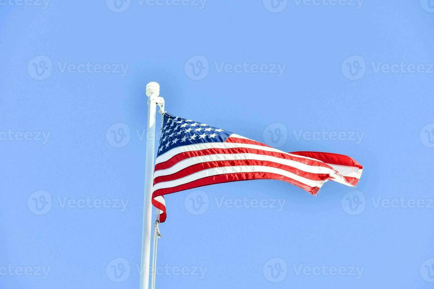 an american flag flying in the wind against a blue sky photo