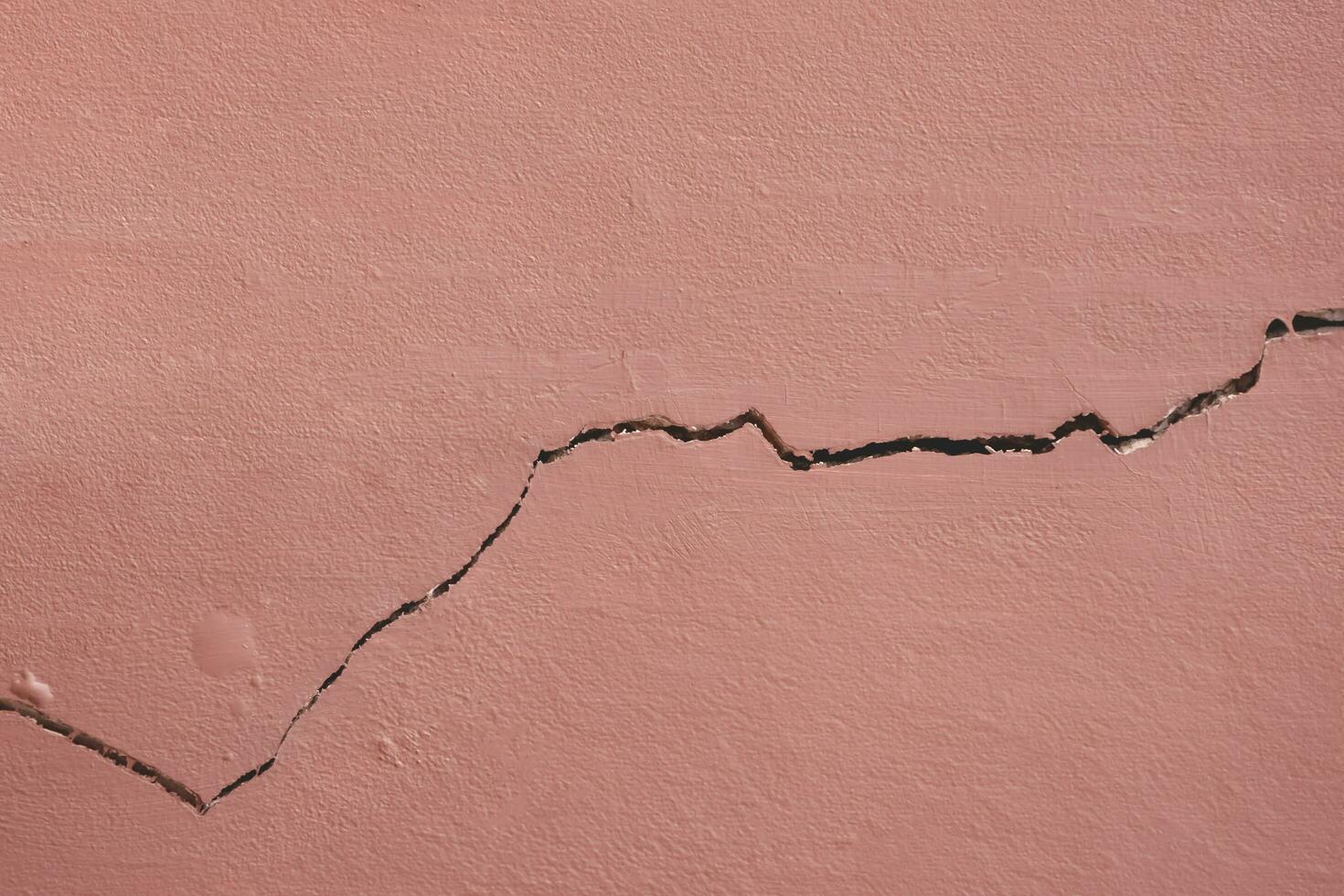 Background and texture of horizontal crack line on surface of brown concrete house wall photo