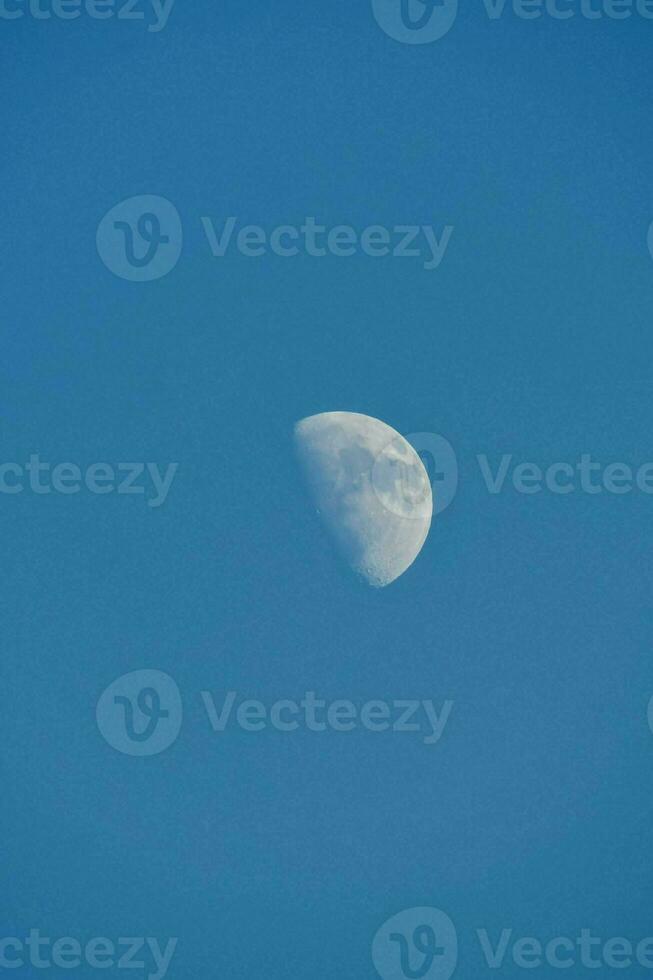 the moon is seen in a blue sky photo