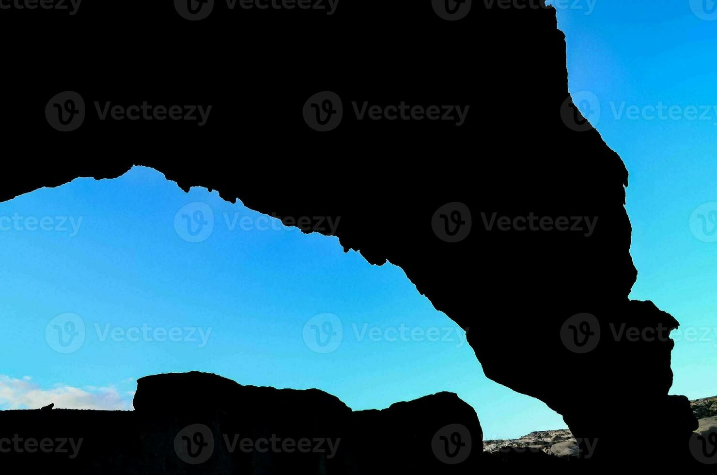 a silhouette of an arched rock formation photo