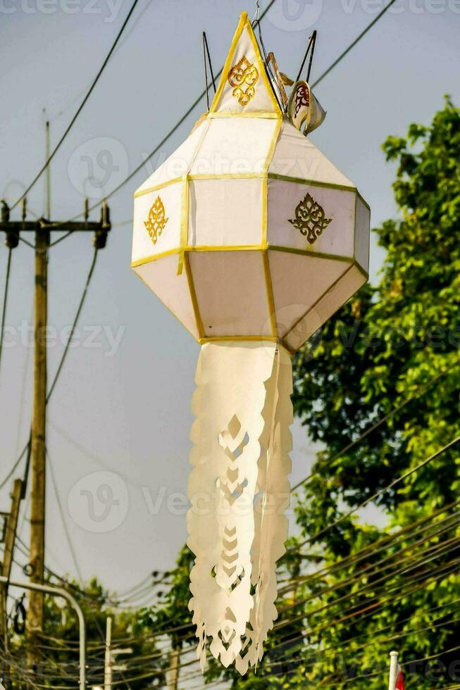 a lantern with a gold design hanging from a power line photo