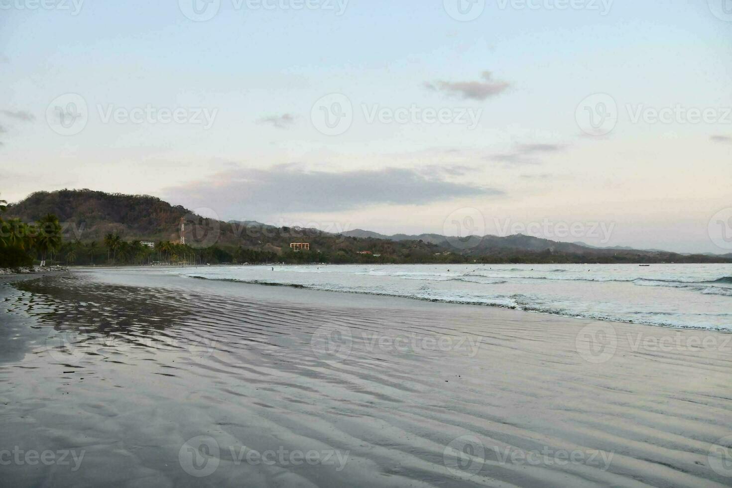 a beach with waves and mountains in the background photo