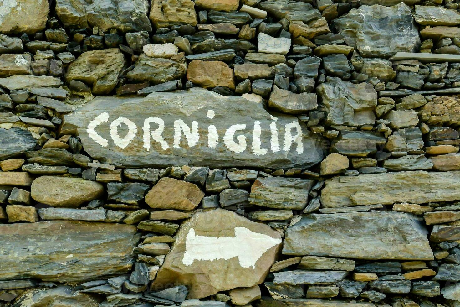 corniglia sign on stone wall photo