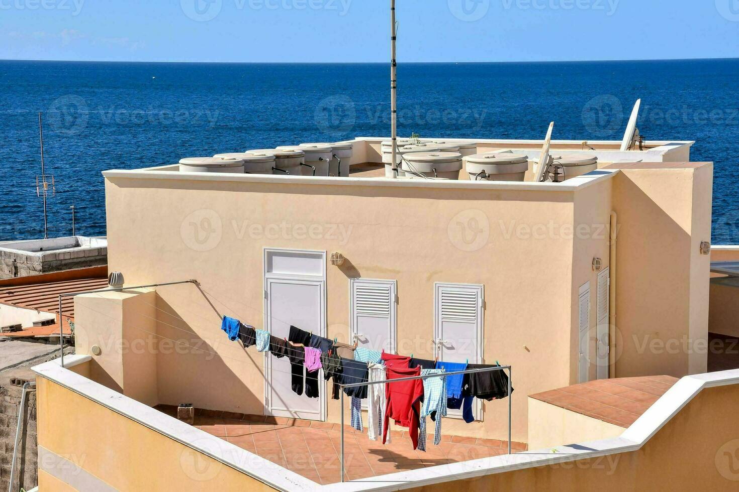 a laundry line on the roof of a building with the ocean in the background photo