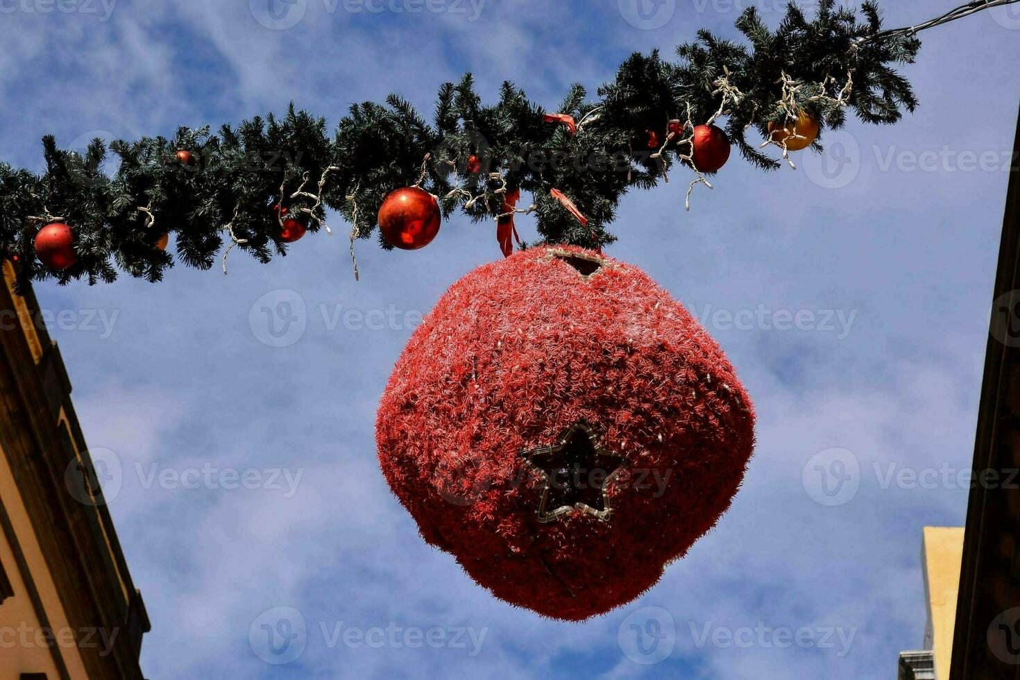 a large red christmas ball hanging from a garland wire photo