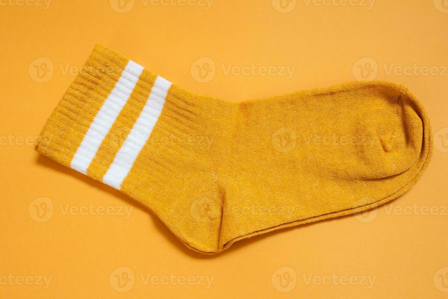 Orange sock isolated on orange background. Top view. photo