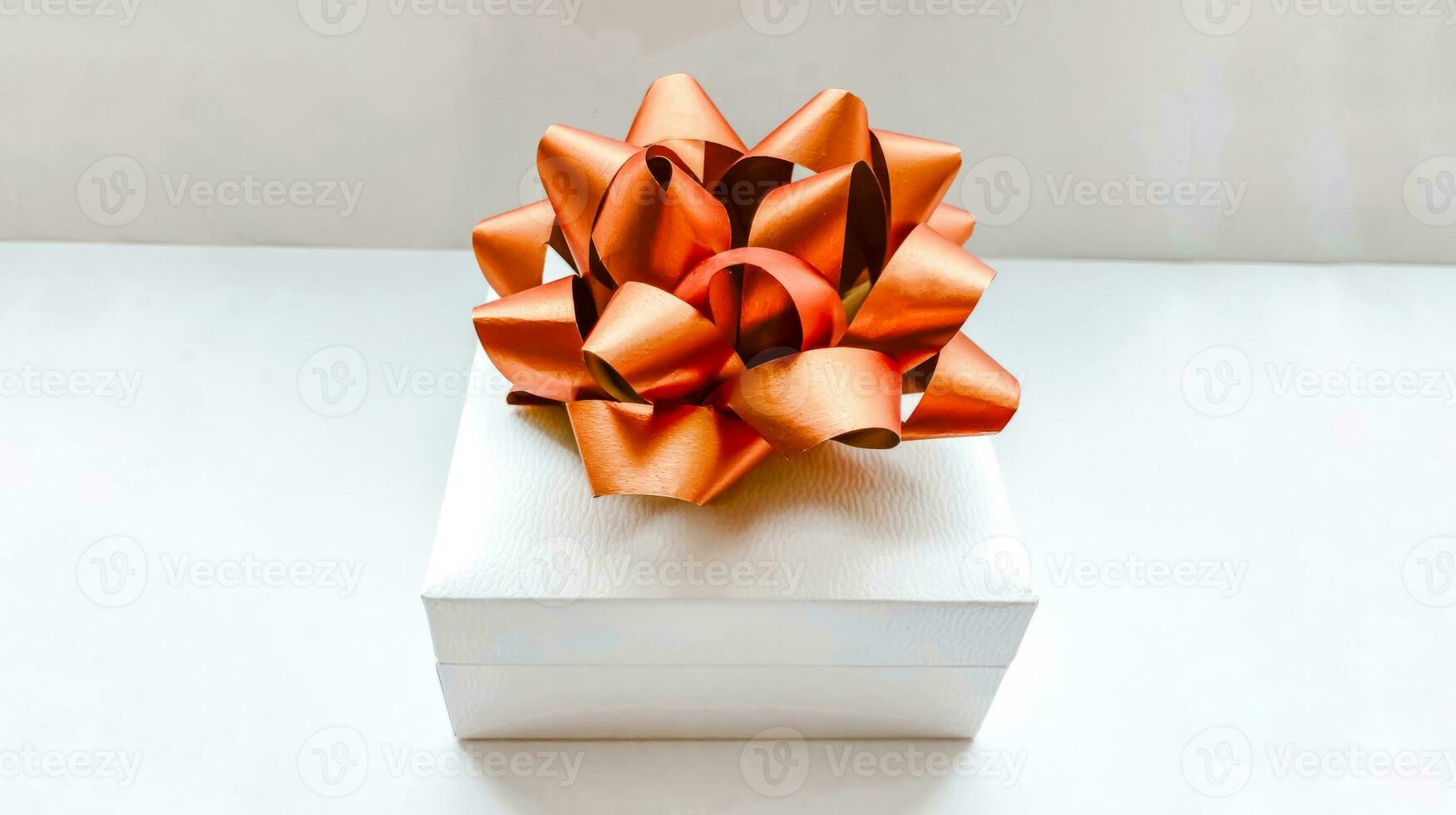 White gift box with a gold bow on a white background. Holiday concept photo