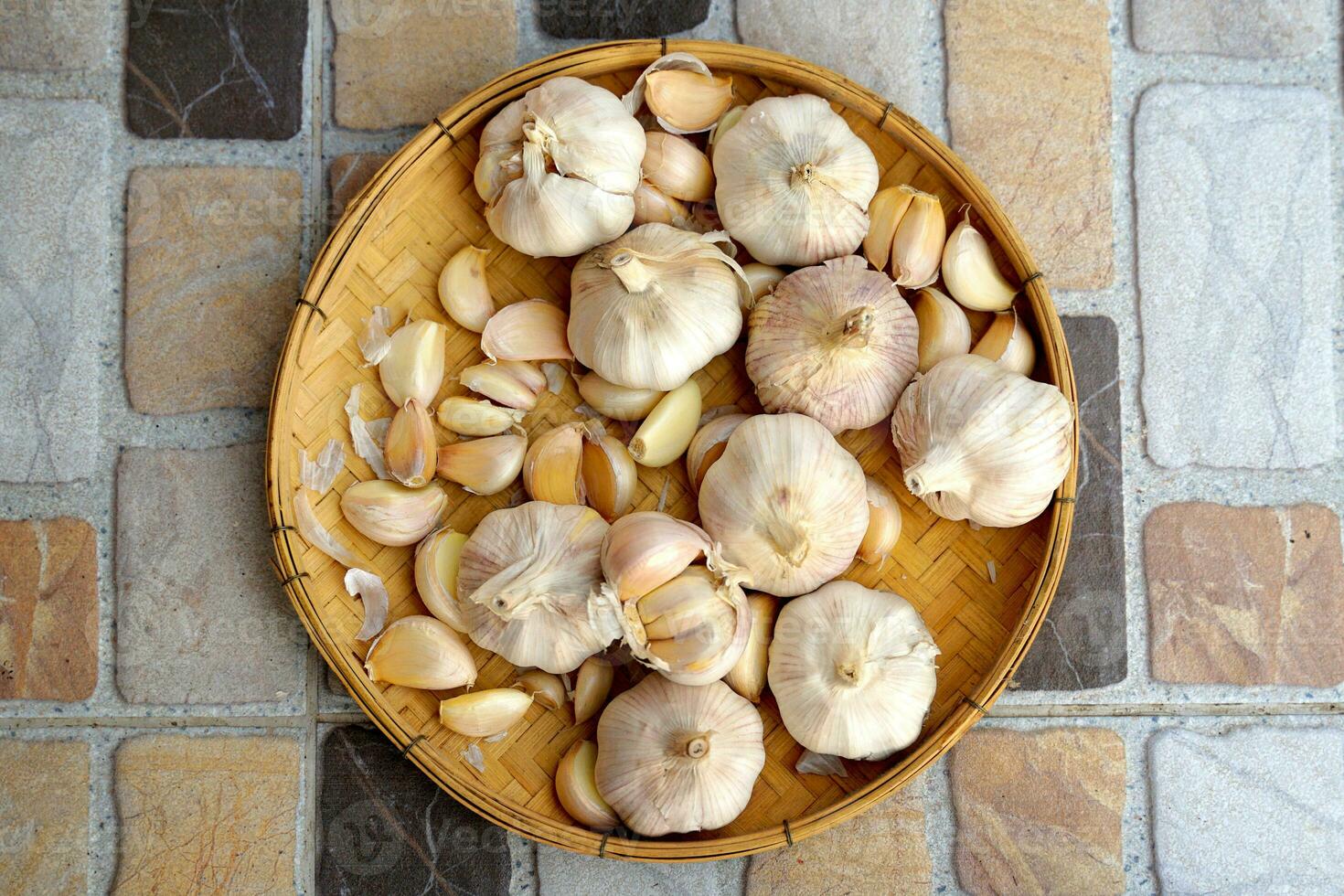 Garlic in a bamboo basket on a white background It is a medicinal plant in Thai kitchens used as an ingredient in food. It has a pungent odor and a spicy taste. It can be eaten both fresh and cooked. photo