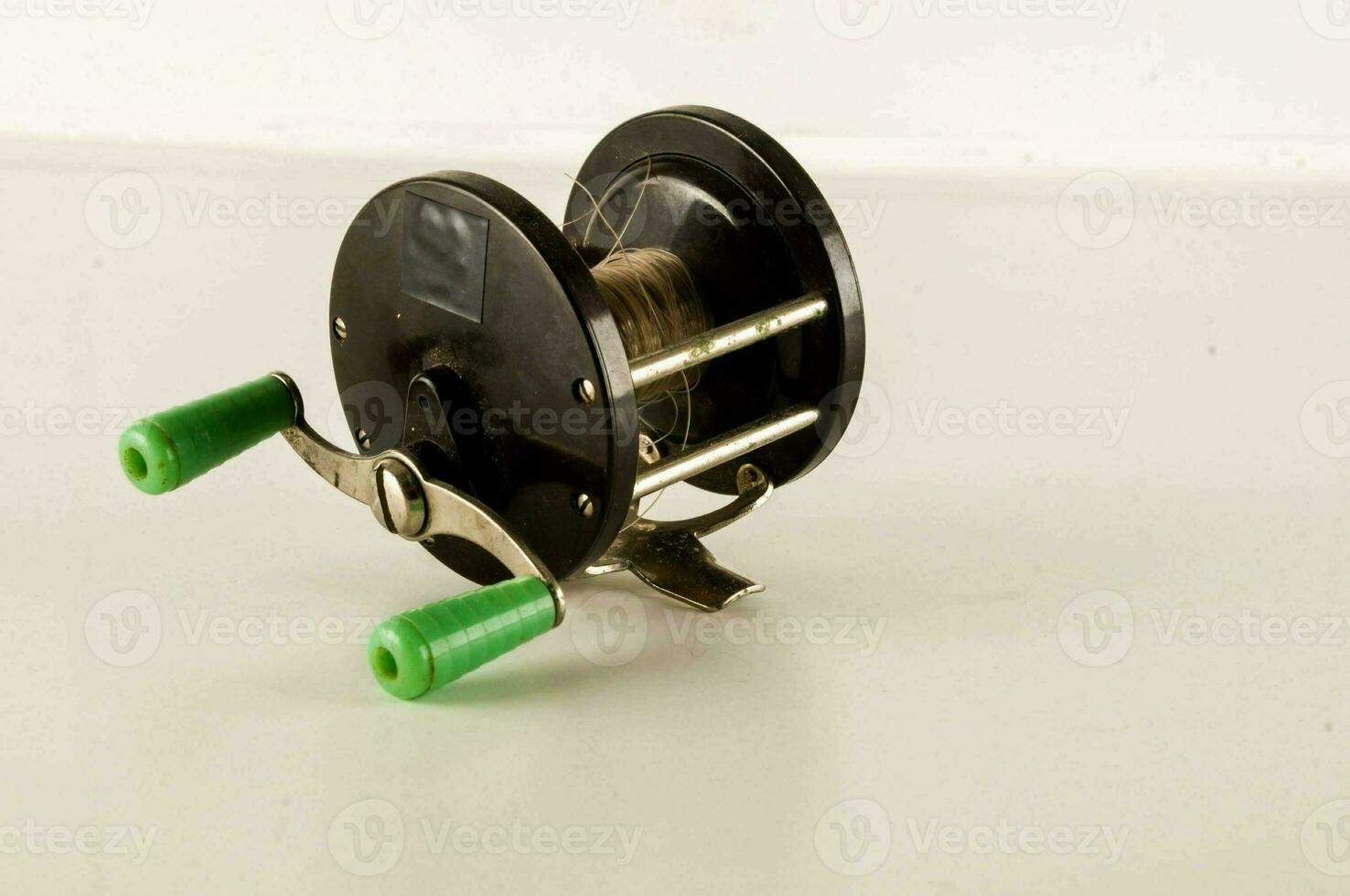 a reel with green handles on a white surface photo