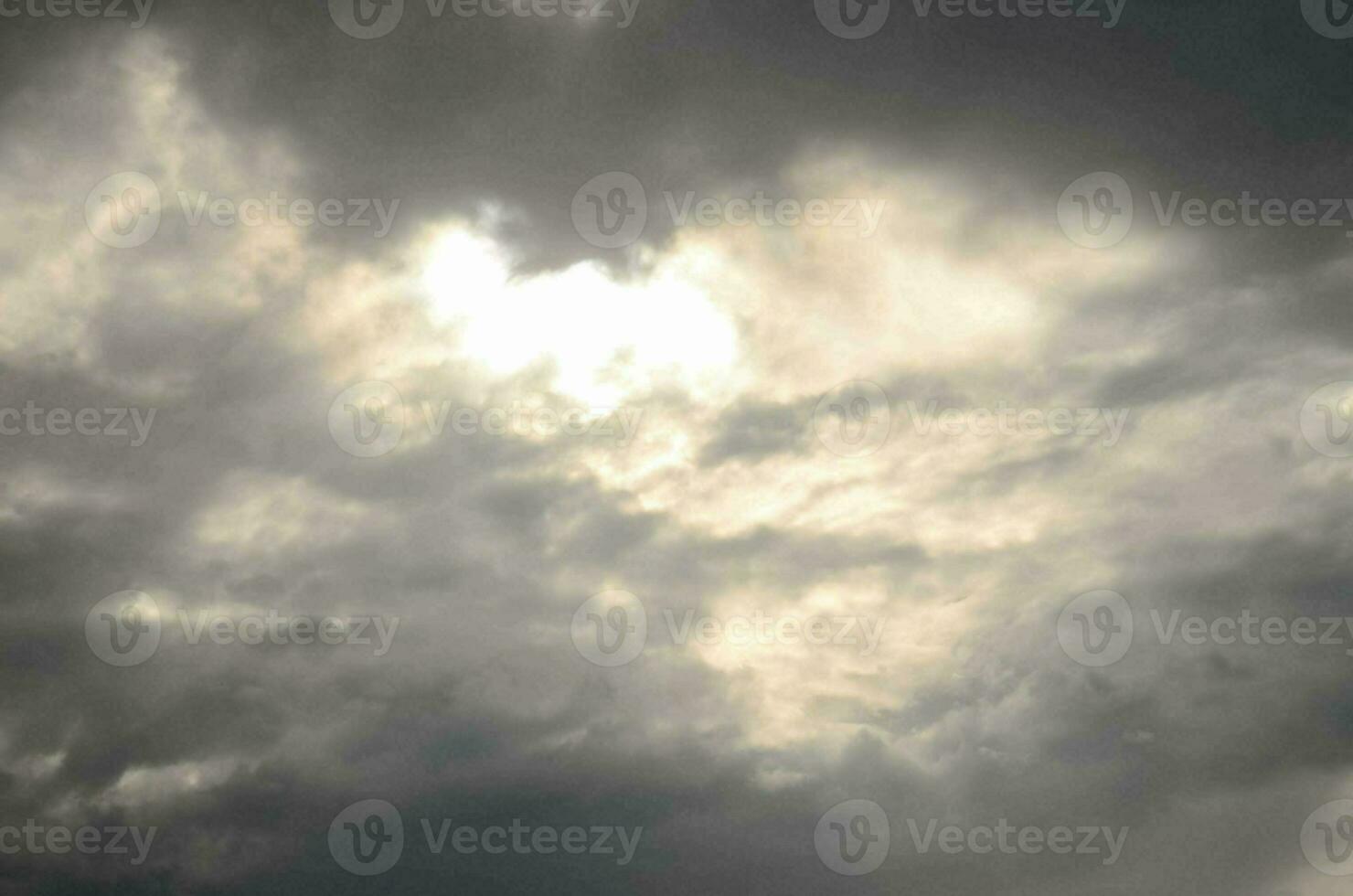 a dark cloudy sky with a sun shining through photo