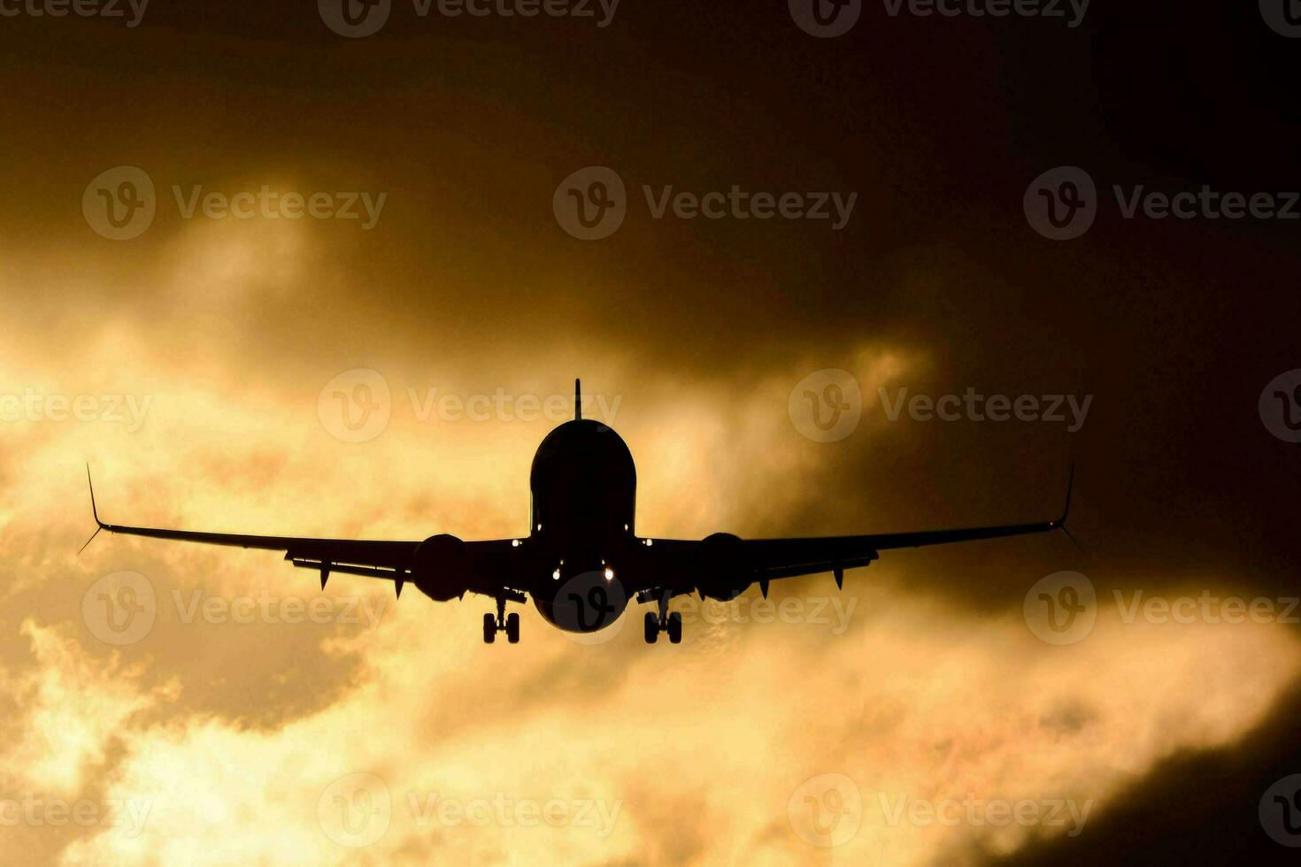 a passenger jet is silhouetted against a cloudy sky photo