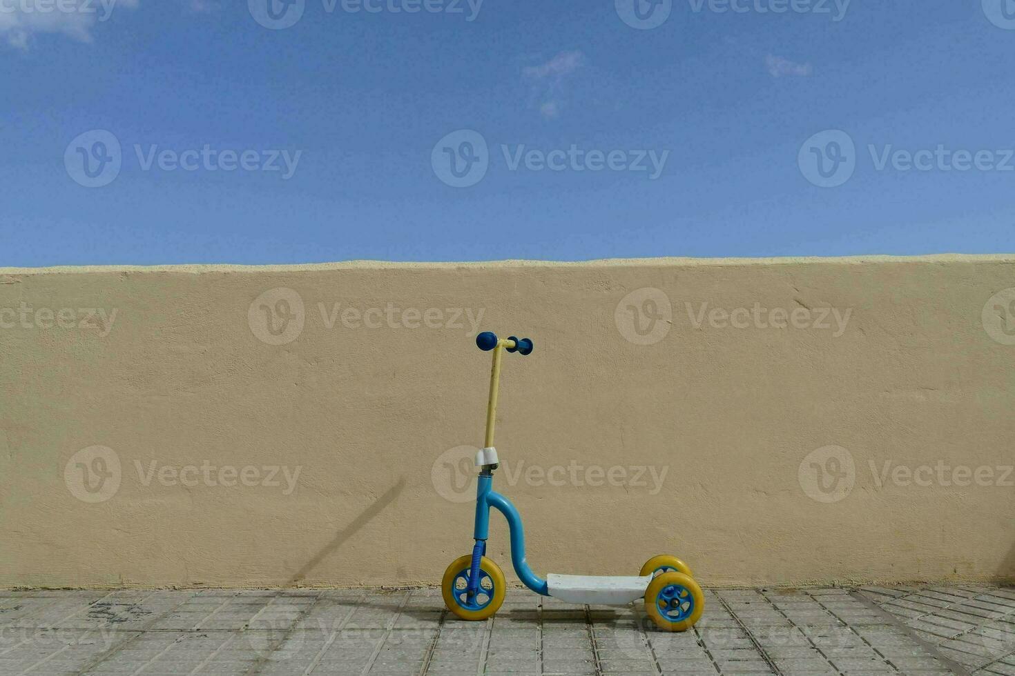 a blue and yellow scooter against a yellow wall photo