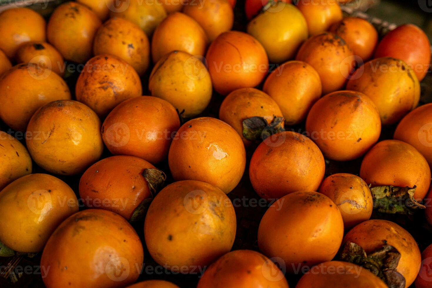 Ripe orange persimmons. on the table in the market. A bunch of organic persimmon fruits at a local farmers market in Dalat city, Vietnam. Persimmon background. Flat lay. photo