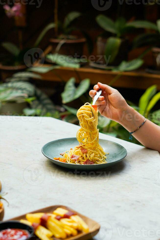 the hand that is lifting the spaghetti on the plate photo