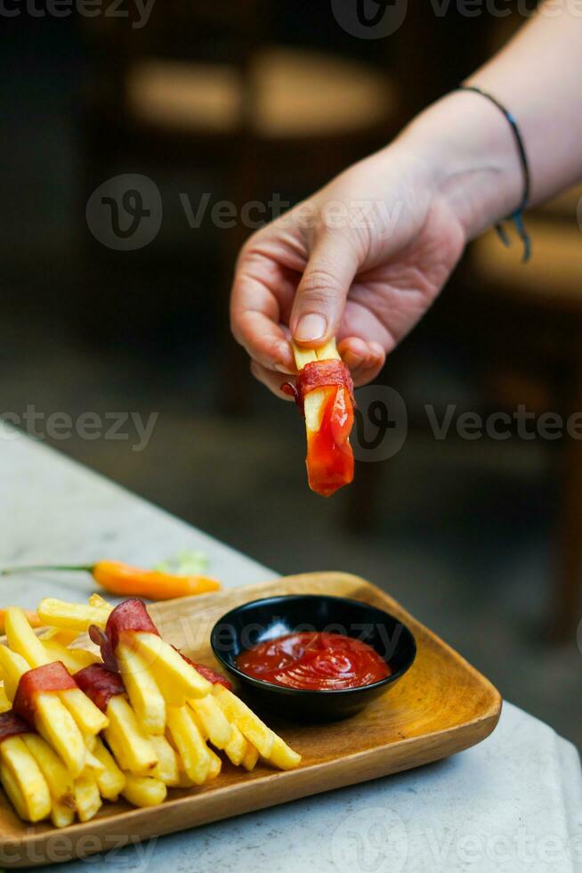 cropped hand dipping potato slice to sauce close up photo