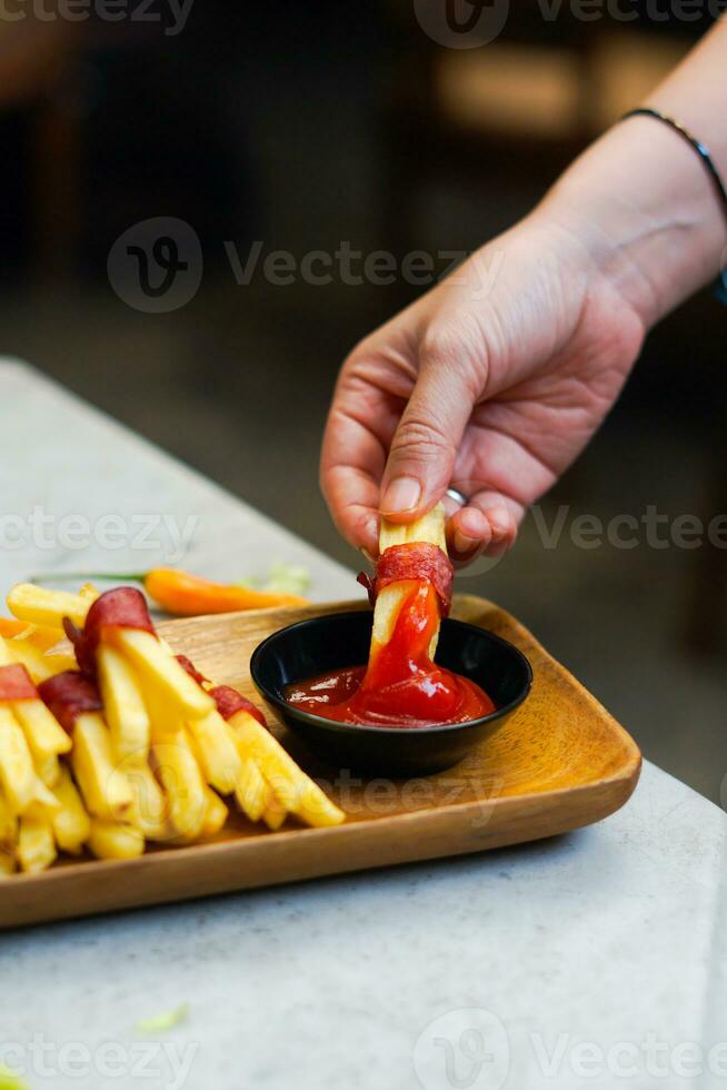 cropped hand dipping potato slice to sauce close up photo