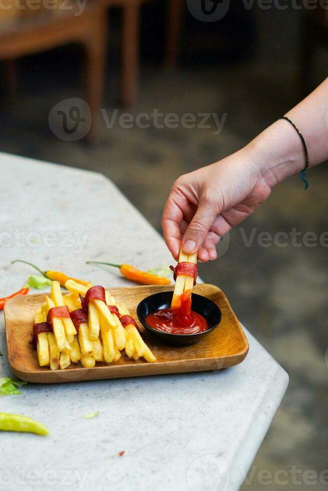 cropped hand dipping potato slice to sauce close up photo