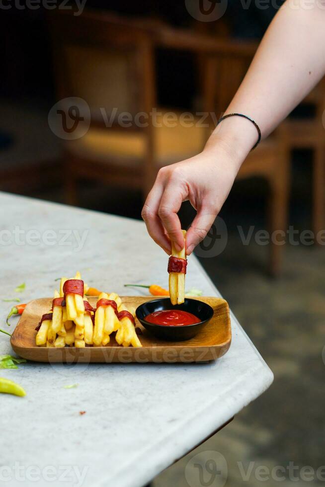 cropped hand dipping potato slice to sauce close up photo