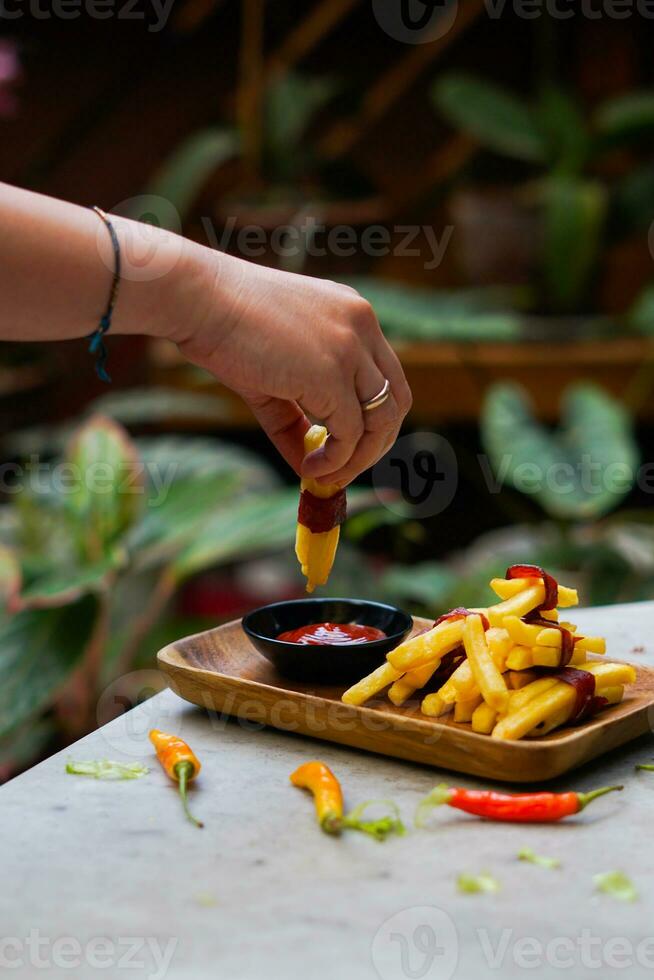 recortado mano inmersión patata rebanada a salsa cerca arriba foto