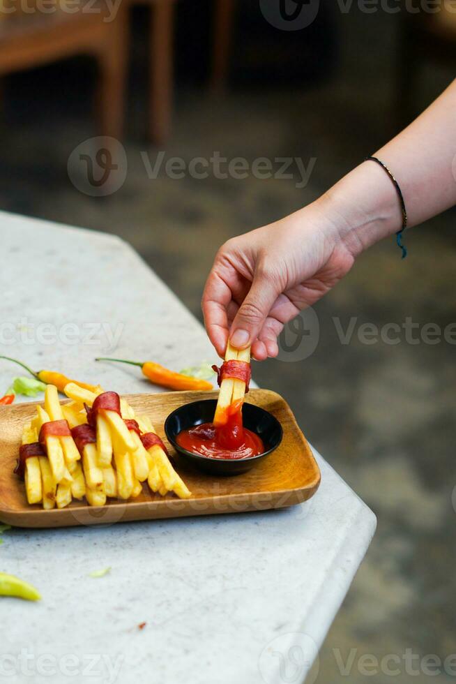 cropped hand dipping potato slice to sauce close up photo