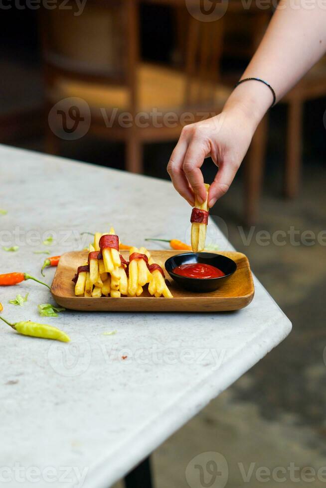 cropped hand dipping potato slice to sauce close up photo