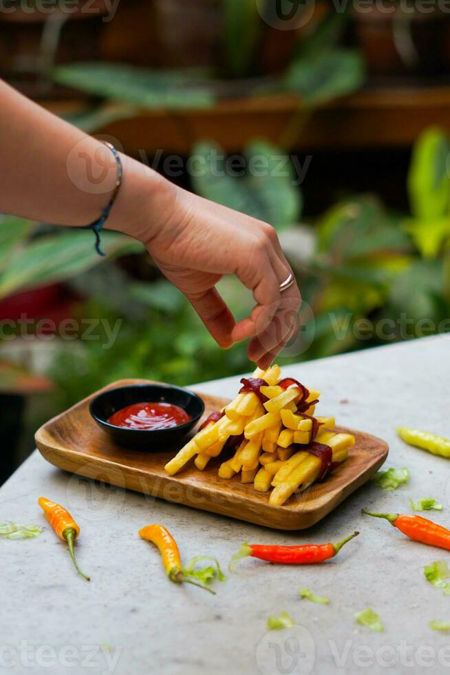 recortado mano inmersión patata rebanada a salsa cerca arriba foto