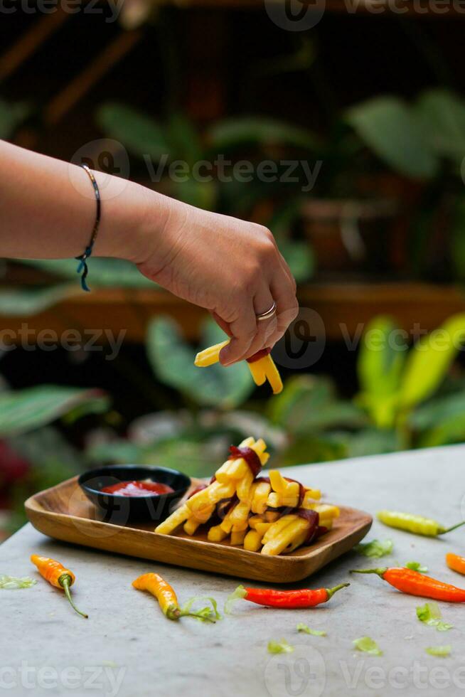 cropped hand dipping potato slice to sauce close up photo