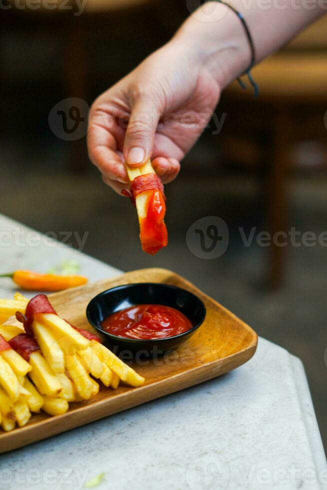 cropped hand dipping potato slice to sauce close up photo