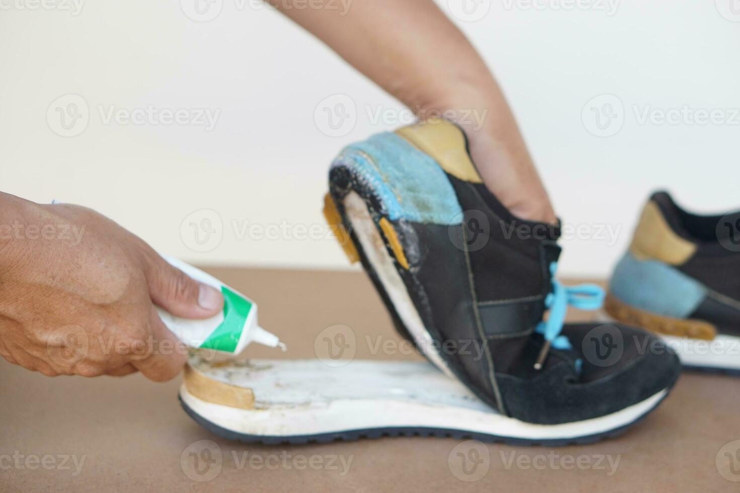 Closeup man hand use super glue to fix broken shoe. Concept, repair for reuse or recycle footwears before being garbage. photo