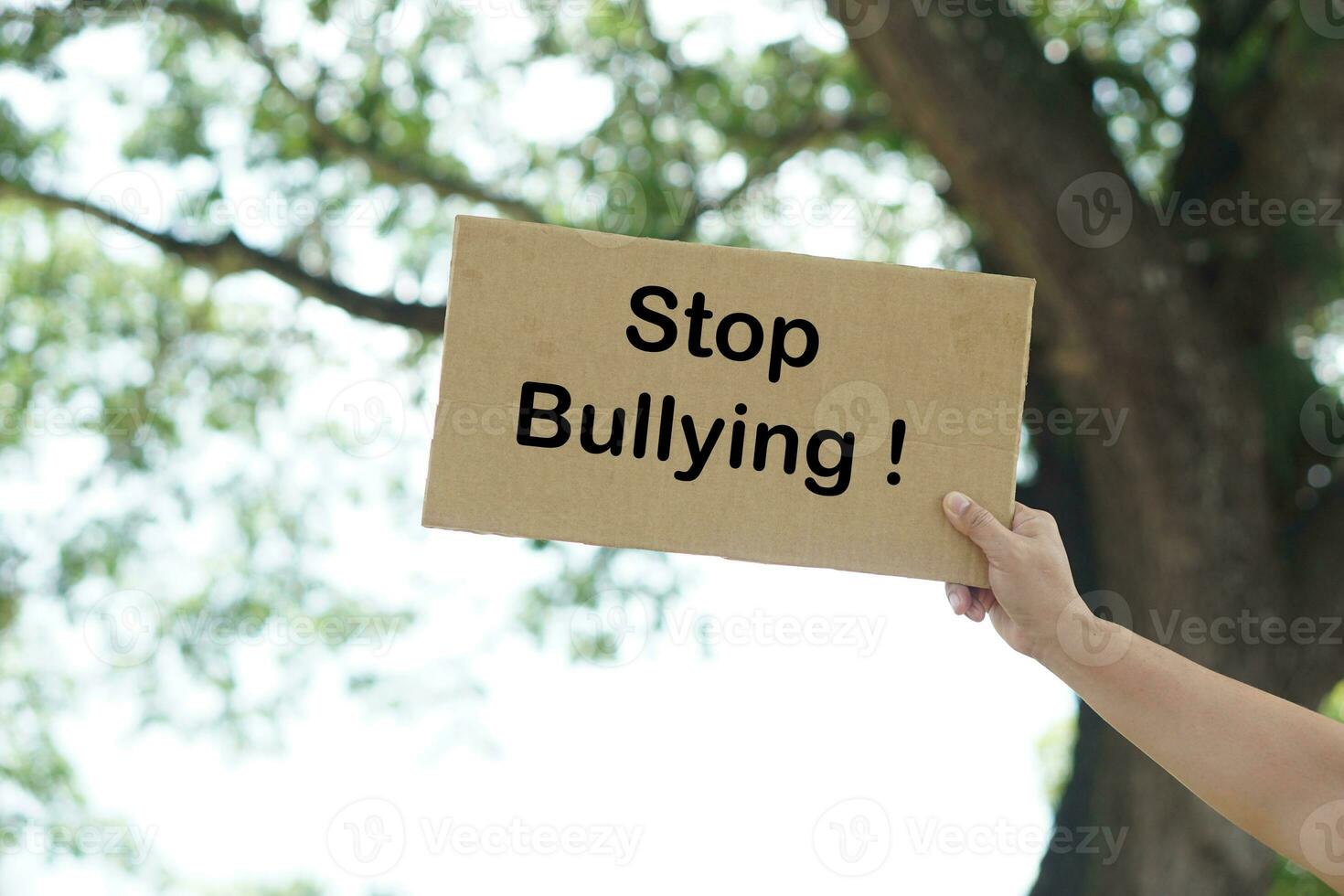 Close up hand holds paper placard with text Stop Bullying, outdoor