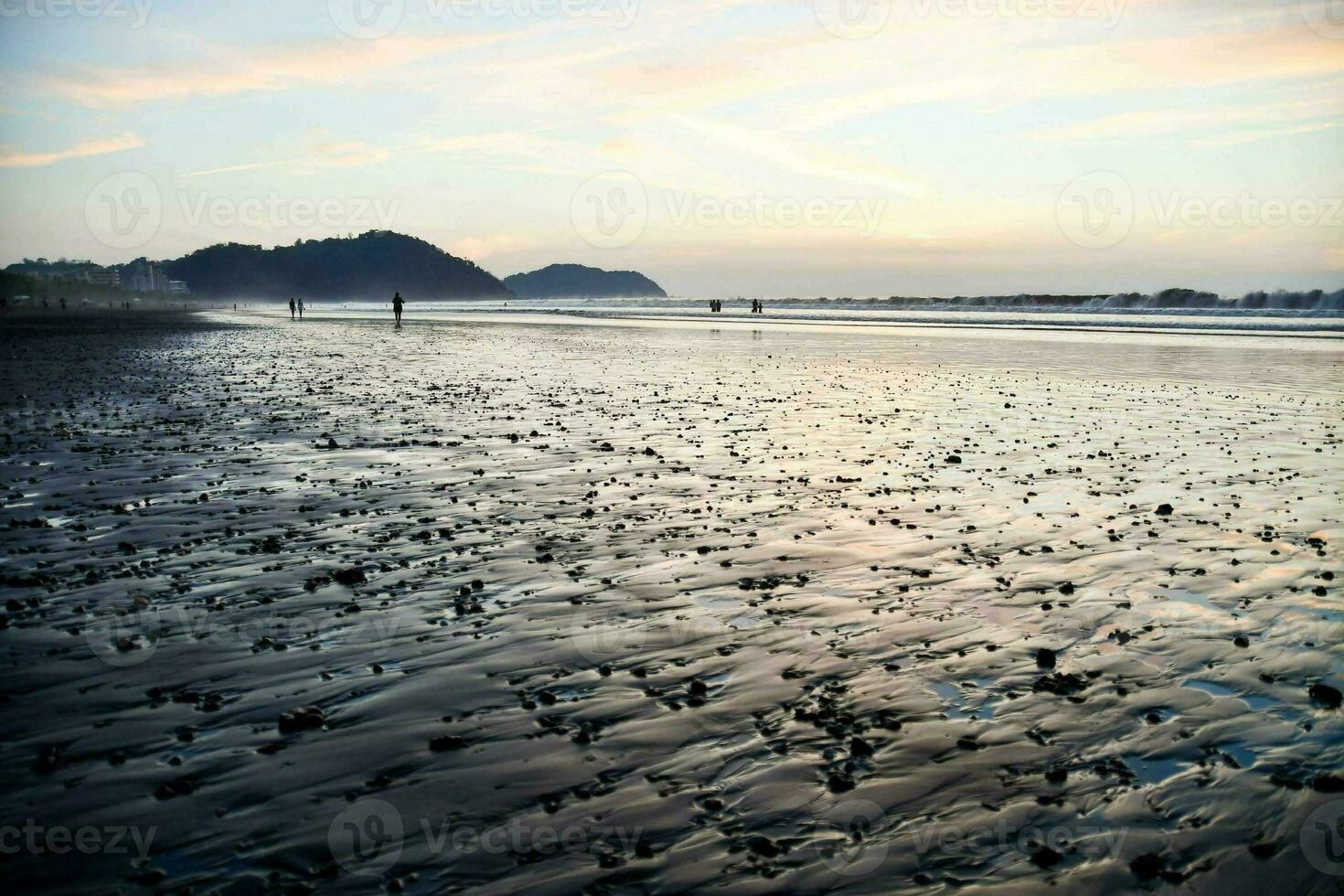 a beach with black sand and water at sunset photo