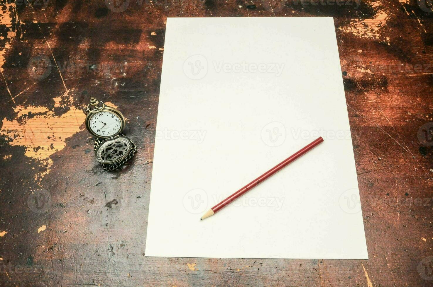 a white sheet of paper with a red pencil on top of a wooden table photo