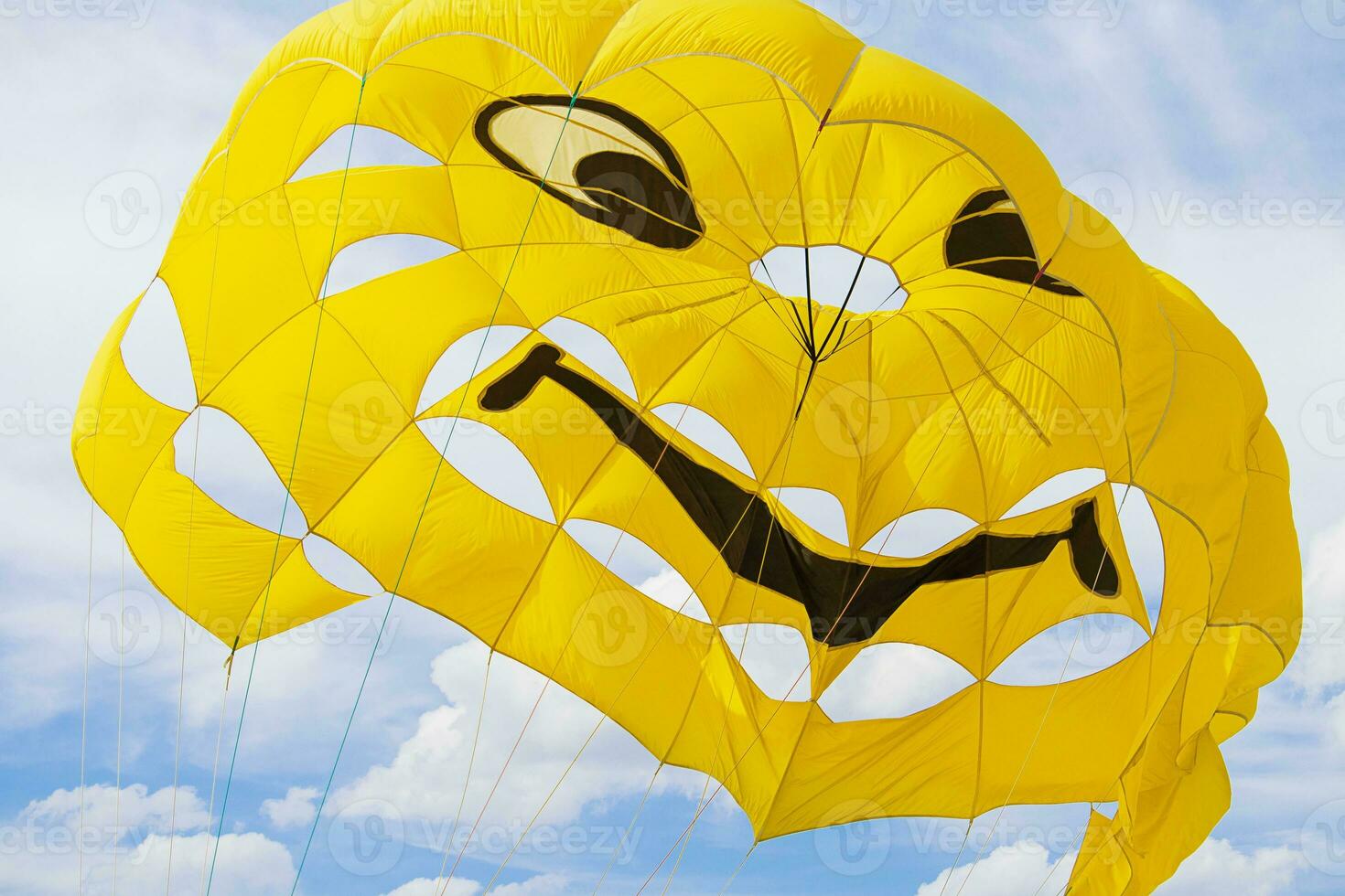 Bright yellow parachute with smile on sky with clouds background. Concept of extreme sport, adventure, challenge, relaxation photo