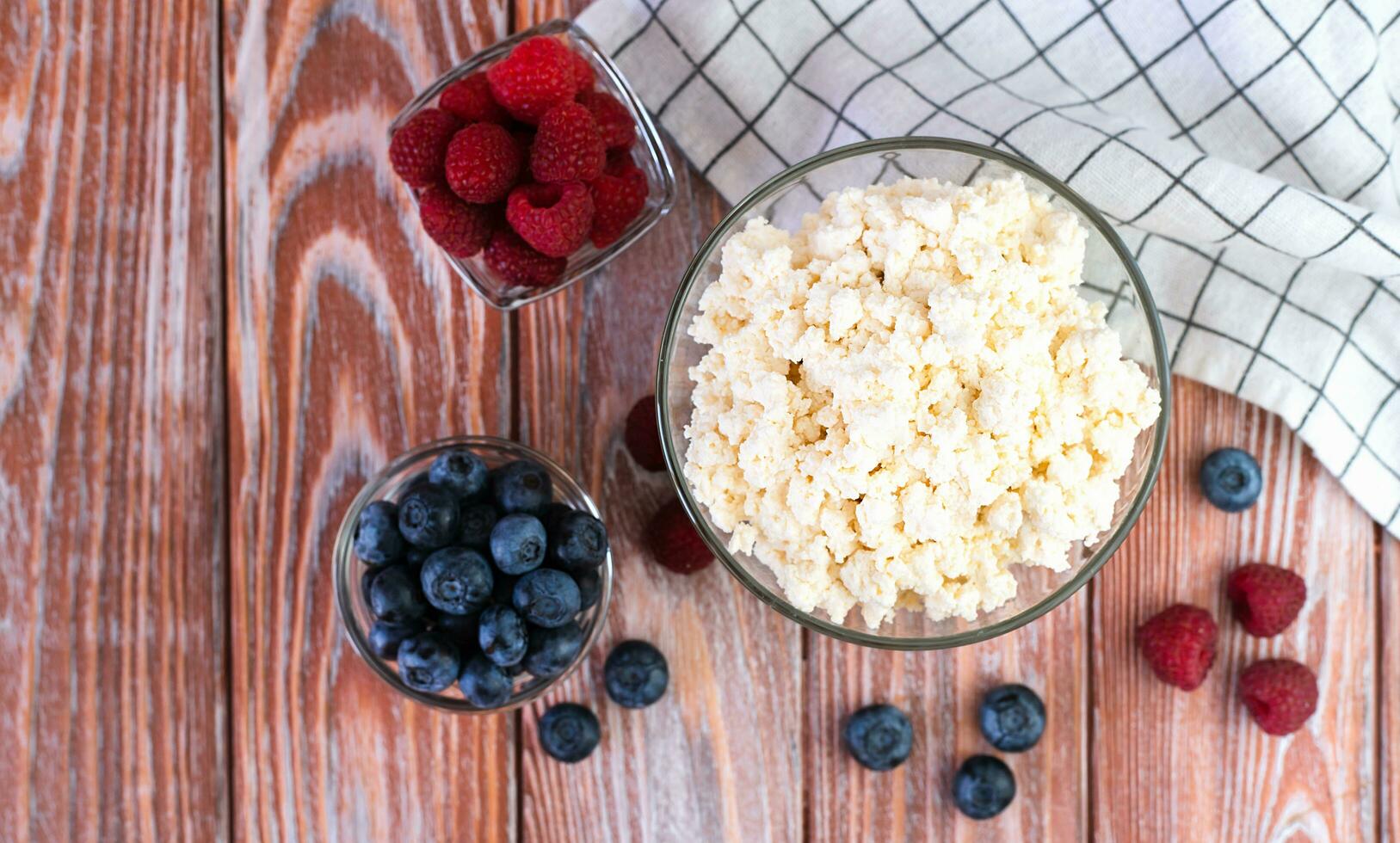 Cottage cheese and ripe berries on the wooden table for breakfast. Close-up. Top view. Copy space. photo