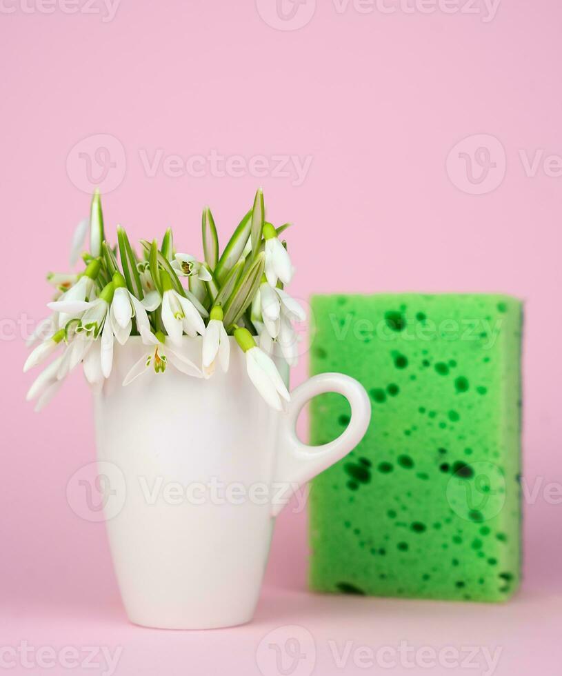 Minimalist composition with spring flowers and kitchen sponge on a pink background. Cleaning concept. Close-up. Selective focus. photo