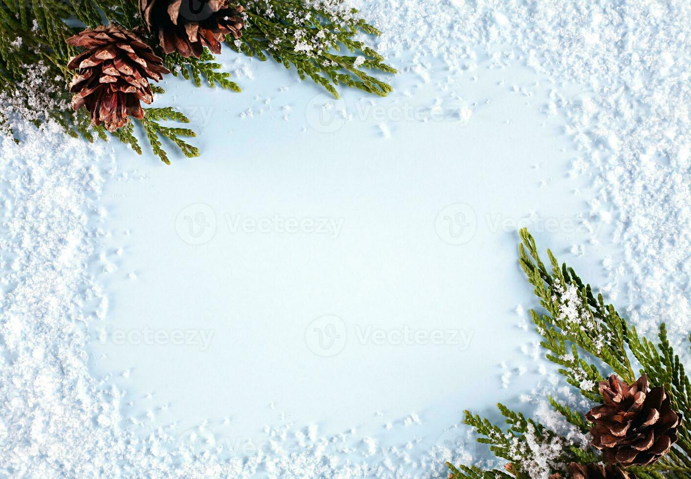 Christmas or winter composition. Frame made of snow, fir branches and fir cones on blue background. New year greeting card. Christmas or New Year flatlay. Top view. Copy space. photo
