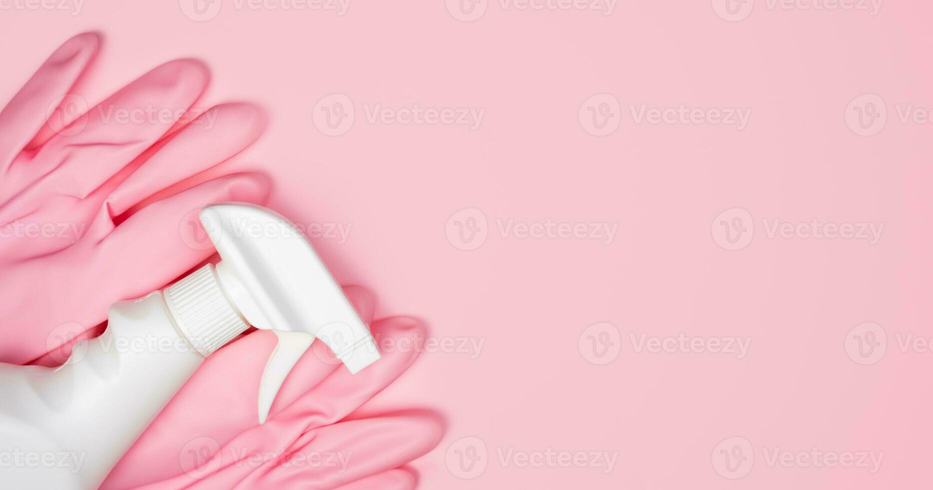Pink rubber gloves and spray cleaner on a pink background. Flatlay. Banner. Close-up. Top view. Place for text. photo