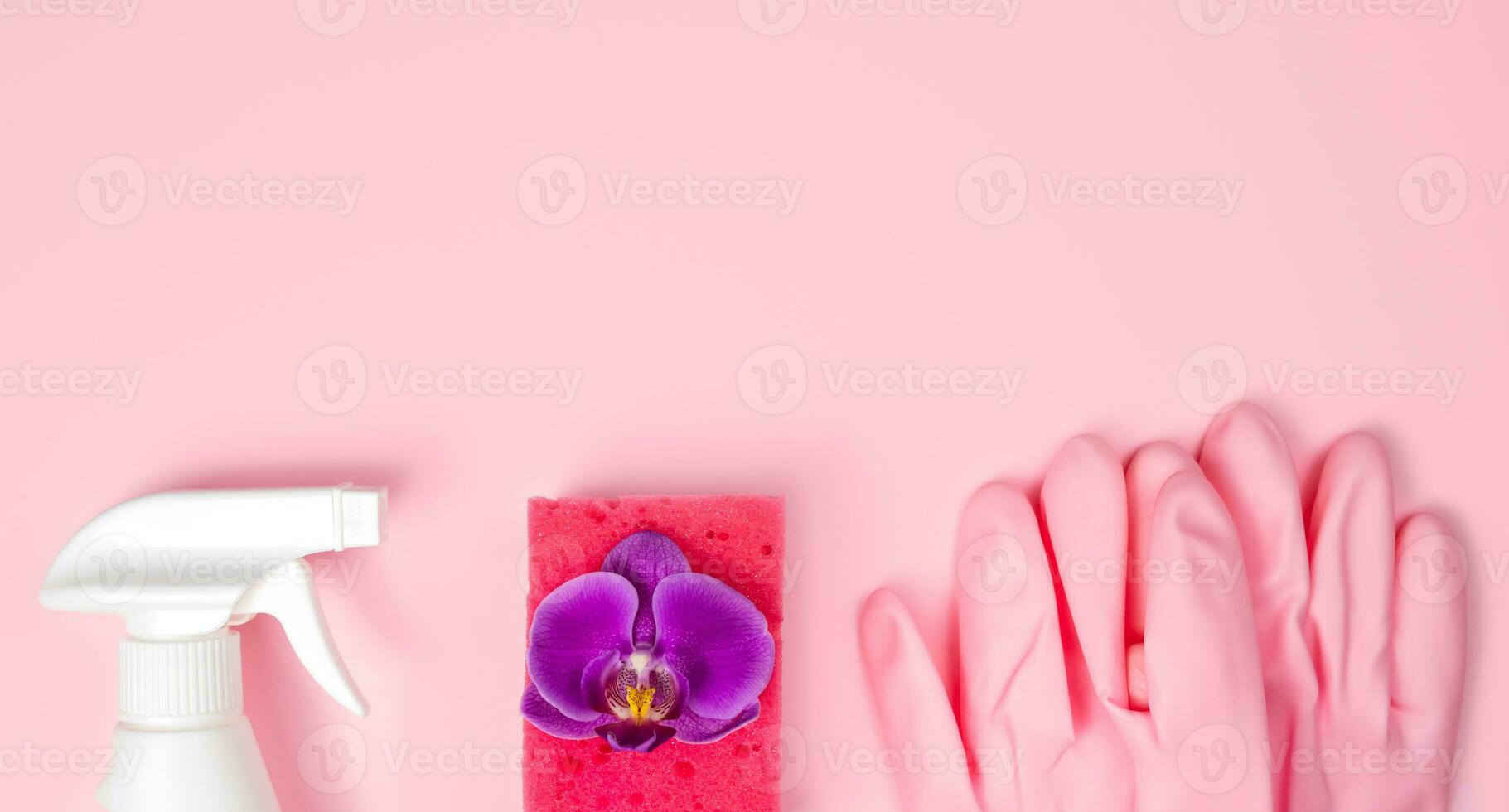 Spring cleaning concept. Detergent, orchid flower, kitchen sponge and rubber gloves on a pink background. Flatlay. Banner. Copy space. Top view. photo