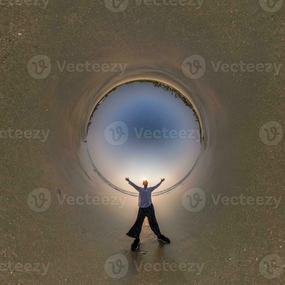 blue hole sphere little planet inside ocean seashore and sands withhappy man stands on coast in rays of evening tropical sun with transformation of spherical panorama 360 degrees. urvature of space. photo