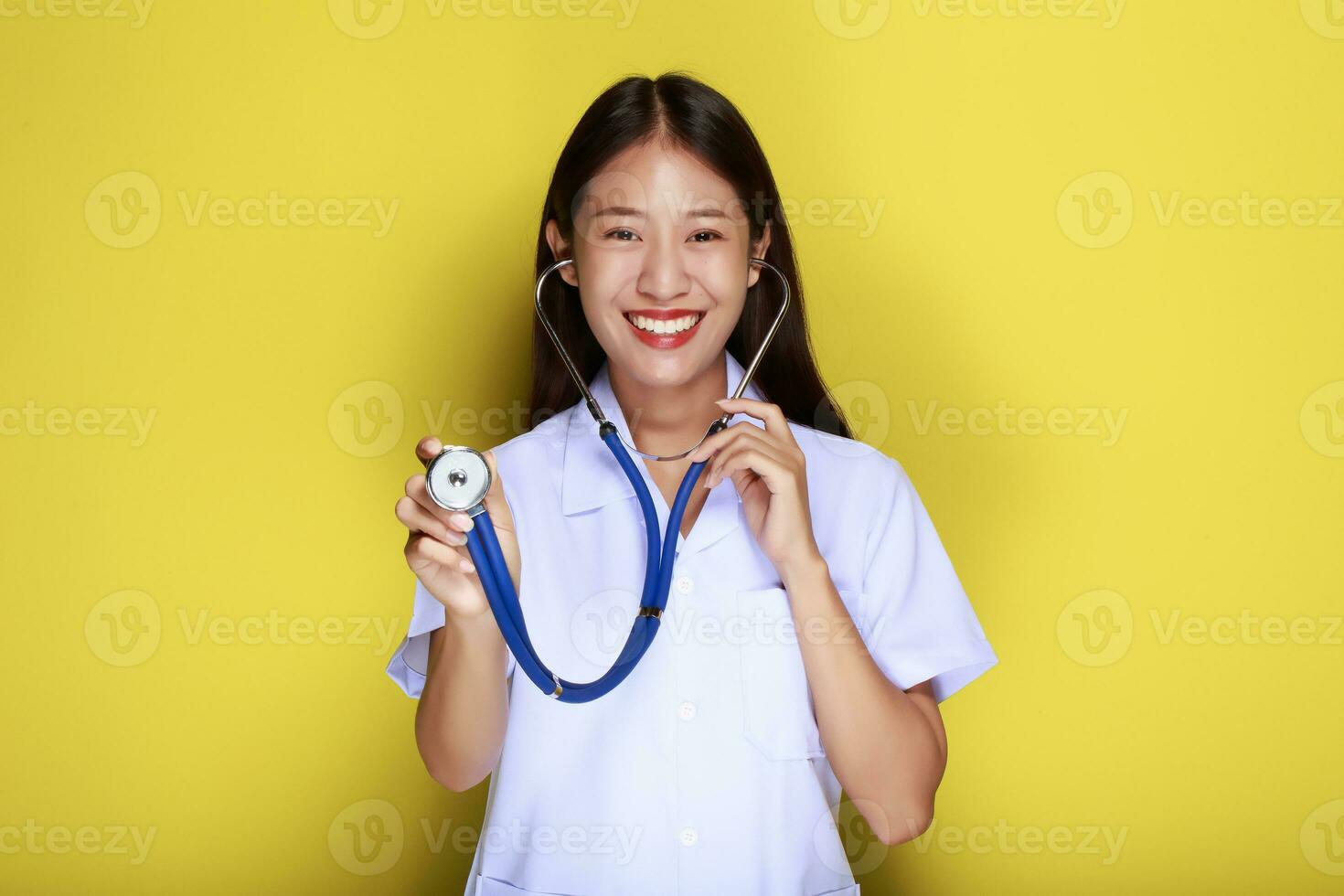 Portrait of a beautiful young woman in a yellow background,  Asian woman wearing a doctor's uniform makes a smiling expression, A young woman wearing a medical stethoscope has a friendly expression. photo