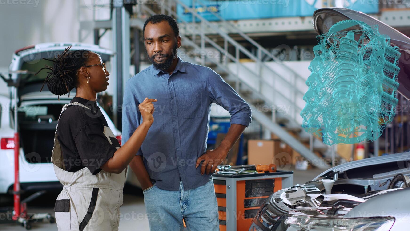 Repairman in car service using augmented reality hologram to show woman defective components inside automobile. Knowledgeable garage worker using high tech AR software to project vehicle motor photo