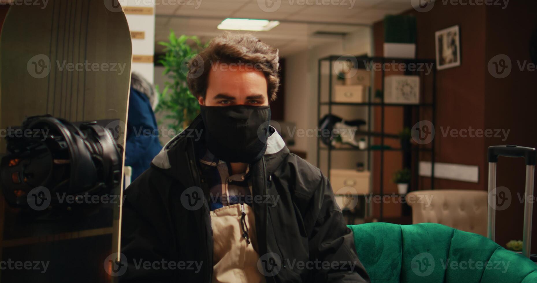 muscular persona viniendo a montaña ubicación a comienzo esquiar con engranaje, vistiendo la seguridad invierno vestir y sombrerería antes de practicando intenso deportivo actividades, joven adulto se relaja en vestíbulo. foto