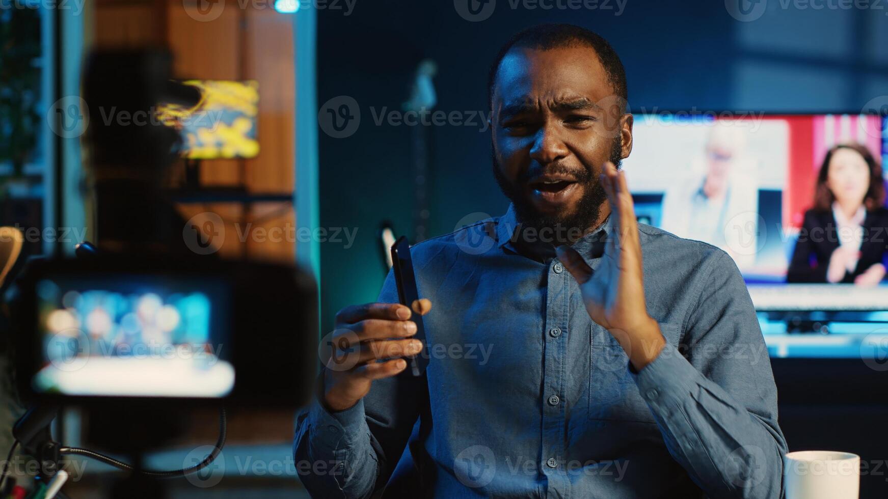 Tech content creator filming review of newly released smartphone, unboxing it and giving feedback to audience. Online star showing mobile phone recommendation to subscribers photo