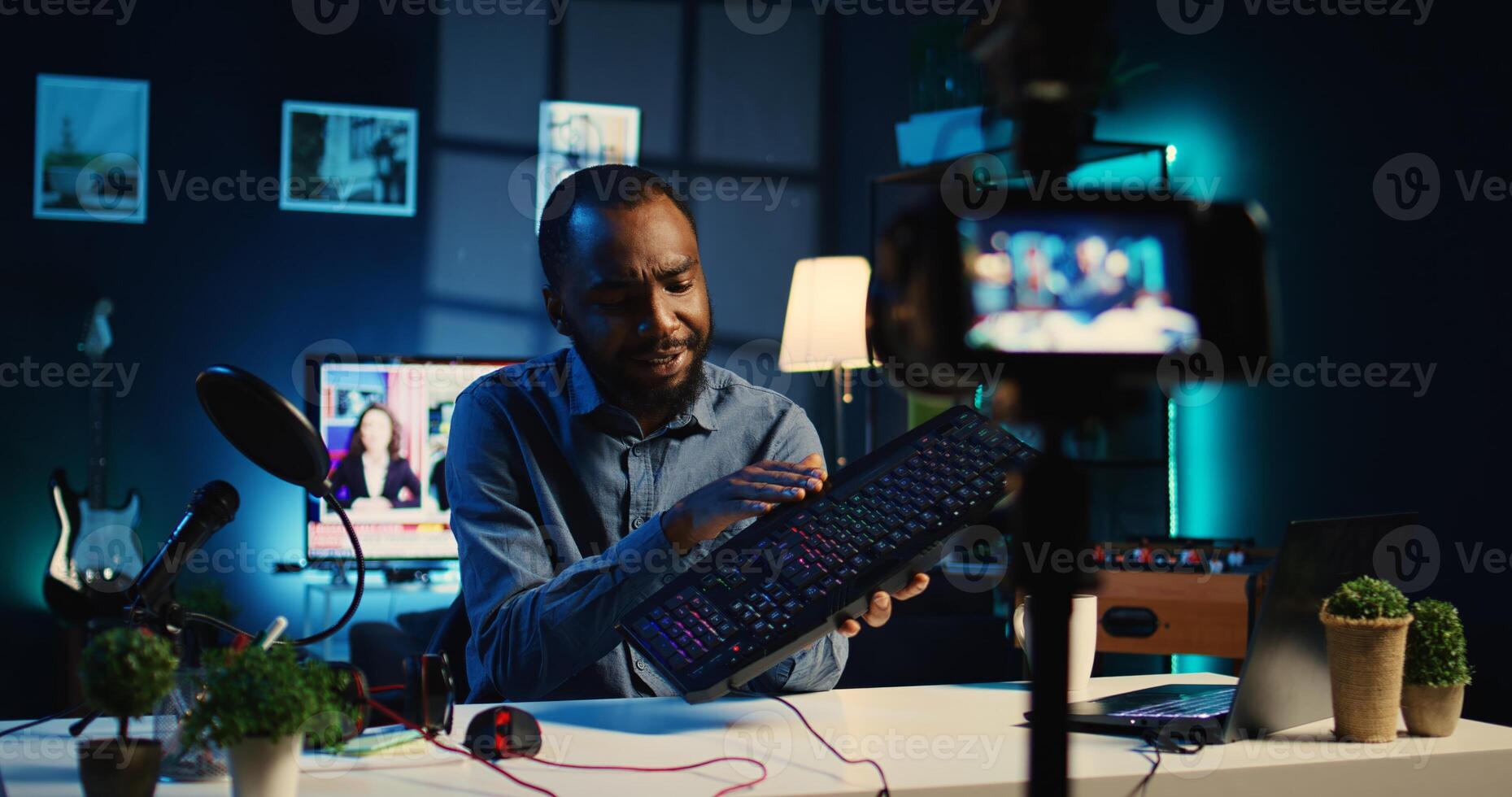 Content creator in dimly lit apartment studio uses professional camera to film keyboard review for online streaming platforms. Online star hosts internet show, unpacking USB wired computer peripheral photo