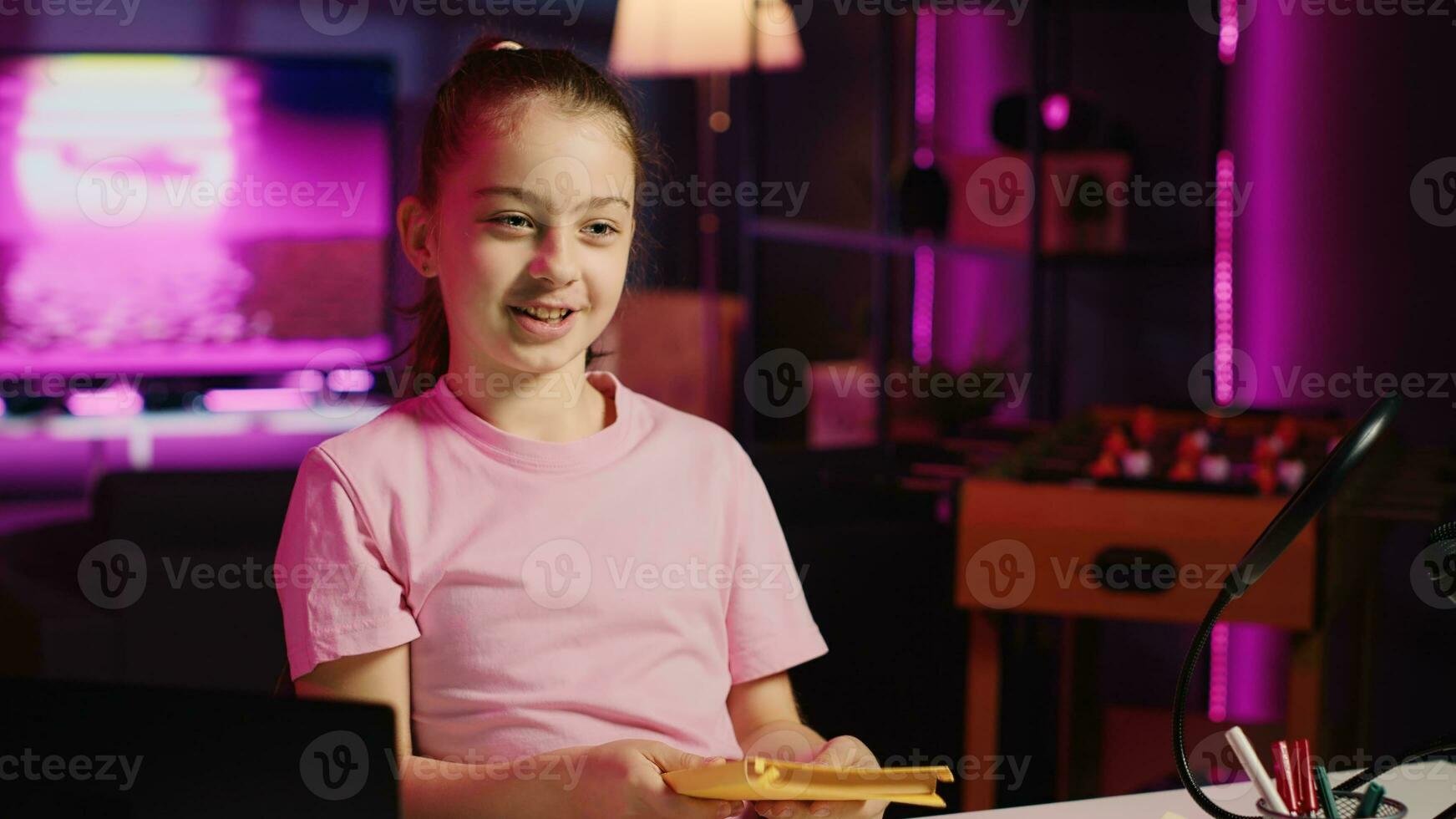 Little girl presenting her new favorite book after receiving it as homework from school. Kid content creator shooting children literature review video for social media channel photo